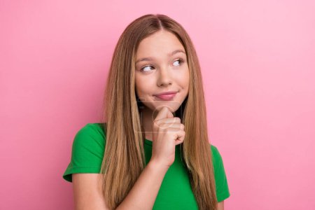 Photo portrait of pretty teenager girl touch chin look empty space wear trendy green outfit isolated on pink color background.