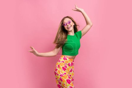 Foto retrato de bastante adolescente bailando celebrar compras promo desgaste traje verde de moda aislado sobre fondo de color rosa.