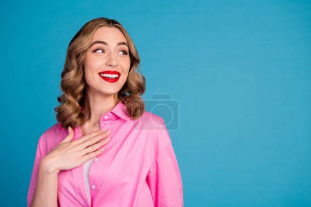Foto-Porträt der schönen jungen Dame sehen interessiert leeren Raum gekleidet stilvolle rosa Kleidungsstück Frisur isoliert auf blauem Hintergrund.