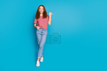 Foto in voller Größe von schönen netten Mädchen tragen stilvolle T-Shirt Jeanshose, die zum Verkauf leeren Raum auf blauem Hintergrund isoliert.