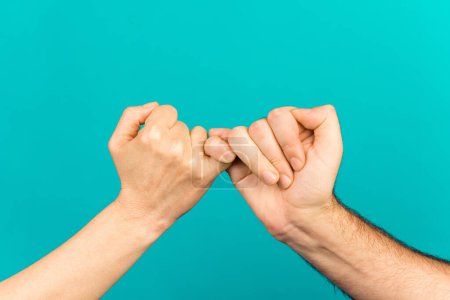 Photo of two people arms palms having fingers crossed reconciliating isolated teal color background.