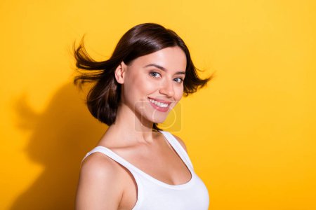 Foto-Porträt von attraktiven jungen Mädchen flatternden Haaren Shopping Promo tragen trendige weiße Outfit isoliert auf gelbem Hintergrund.