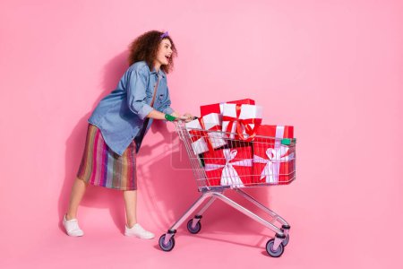 Full length photo of funky impressed lady dressed jeans outfit buying birthday gifts emtpy space isolated pink color background.