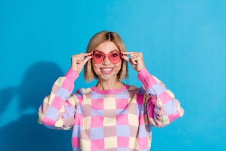 Photo portrait of pretty young girl touch sunglass celebrate party wear trendy pink outfit isolated on blue color background.