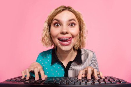 Photo portrait of pretty young girl look excited web camera type keyboard wear trendy striped cyan outfit isolated on pink color background.