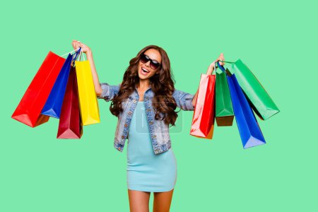 Close up photo beautiful her she lady hands arms enjoy package shopping spree excited amazed low prices wear specs blue teal green short dress jeans denim jacket clothes isolated yellow background.