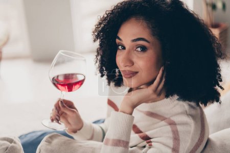 Portrait photo de attrayant jeune femme assise canapé tenir boisson vin verre habillé vêtements décontractés lumière du jour confortable maison salon intérieur.