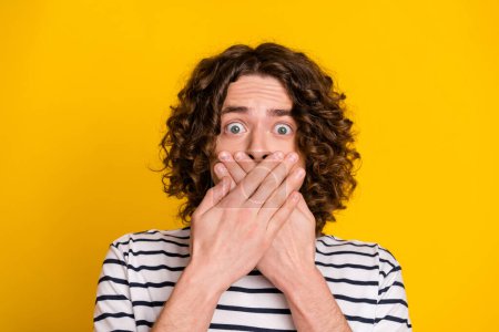 Close up photo of young funny teen guy scared mute his mouth make silence stop talking shut up isolated over yellow color background.