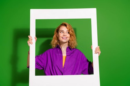 Photo portrait of lovely young lady instant photo frame look empty space dressed stylish violet clothes isolated on green color background.