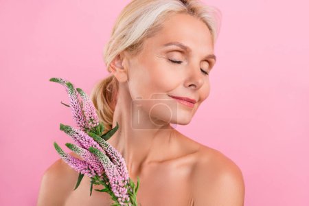 Foto von schönen hübschen fröhlichen Rentnerin Peeling Verfahren reine Haut blumiges Aroma isoliert auf rosa Hintergrund.