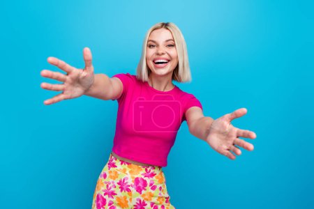 Photo portrait of lovely young lady stretch hands want hug dressed stylish pink clothes isolated on blue color background.