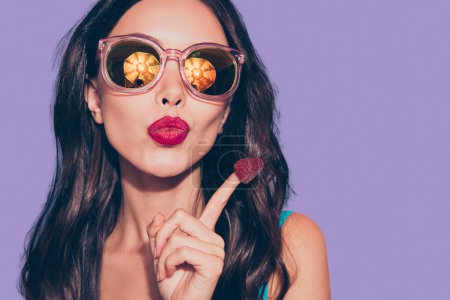 Nahaufnahme Porträt von schön cool attraktiv glamourös charmant bezaubernde wellige Dame rote Lippen Beerenhut auf Zeigefinger Nagel Brille Brille isoliert über rosa Pastell Hintergrund.