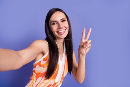 Photo of pretty cute lady wear dress recording video showing v-sign isolated purple color background.