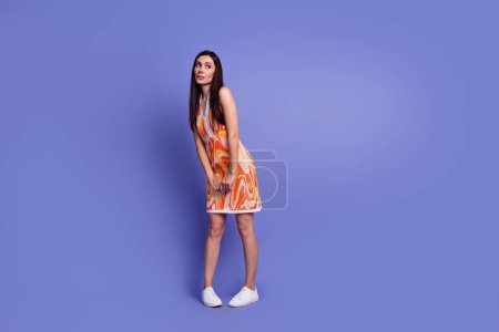 Full size photo of pretty young woman look empty space ponder wear dress isolated on violet color background.