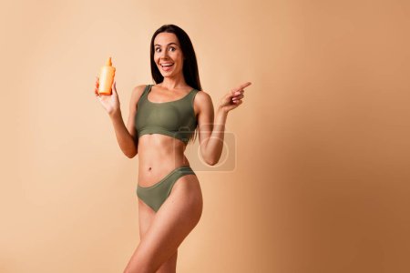 Photo of amazed girl in lingerie hold daily hygiene cream recommend point empty space isolated pastel color background.