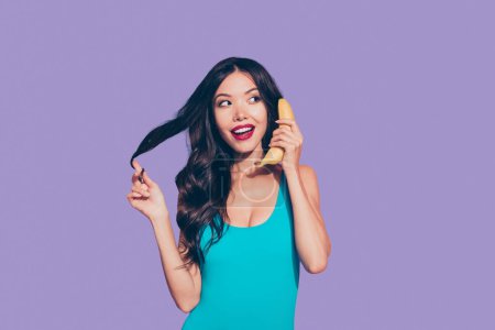 Portrait of nice cheerful funky playful cute attractive charming adorable wavy-haired lady red lips holding banana like phone talk speak chat conversation isolated over pink pastel background.
