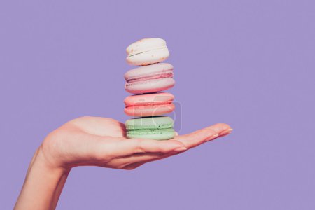 Nahaufnahme ausgeschnitten Foto von weiblichen weiblichen dünne Handfläche halten zeigt zuckerhaltige Dessert Bäckerei bunten Snack isoliert auf rosa Pastell Hintergrund.