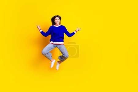 Foto de longitud completa de bastante chica adolescente salto meditar desgaste ropa de punto de moda traje azul aislado sobre fondo de color amarillo.