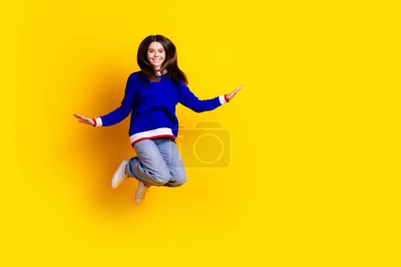Foto de longitud completa de saltos de chica adolescente bonita divertirse desgaste ropa de punto de moda traje azul aislado en el fondo de color amarillo.