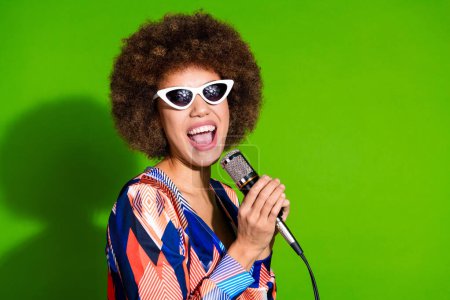 Photo of cheerful adorable woman celebrity wear stylish clothes have fun sing song isolated on green color background.