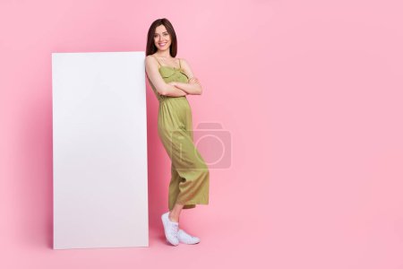 Full body photo of cute positive lady wear stylish khaki outfit stand empty space offer telephone device isolated on pink color background.
