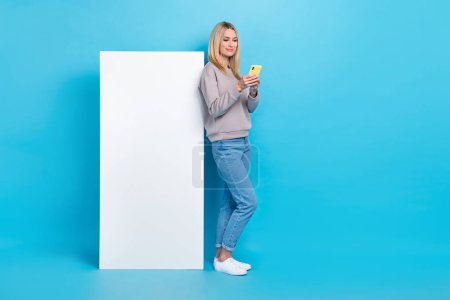 Full length photo of adorable nice lady stylish clothes texting telephone instagram facebook empty space isolated on blue color background.
