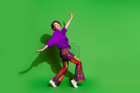Foto-Porträt von lustigen jungen Mädchen Schritte Zehenspitzen in trendigen Outfit fliegen Träumer und braunen Bob-Frisur isoliert auf grünem Hintergrund.