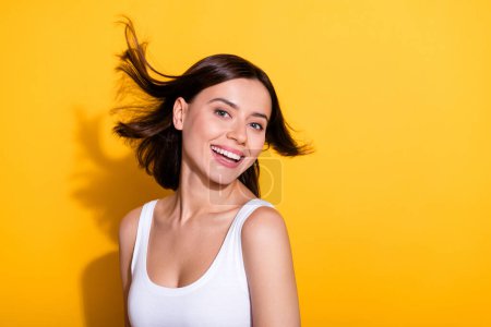 Foto-Porträt von attraktiven jungen Mädchen flatternden Haaren Shopping Promo tragen trendige weiße Outfit isoliert auf gelbem Hintergrund.