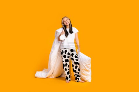 Full length photo of adorable cheerful pretty cute woman wear trendy pajama enjoy weekend isolated on yellow color background.