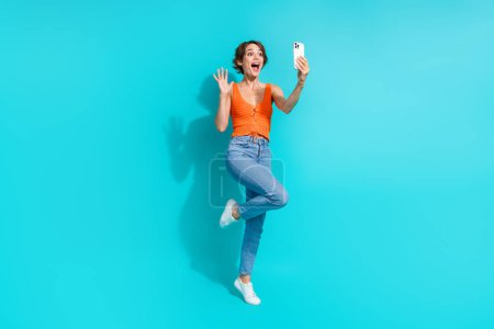 Foto in voller Größe von fröhlichen positiven Mädchen gekleidet Strickwaren Top winkende Hand machen Selfie auf Smartphone isoliert auf blauem Hintergrund.