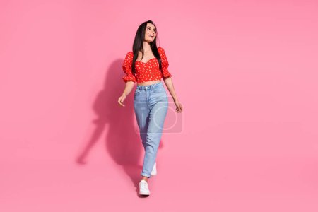 Full body portrait of nice young lady walk look empty space wear top isolated on pink color background.