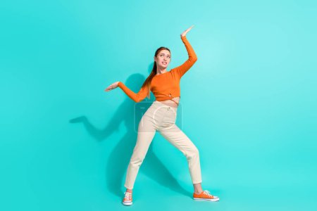 Full length photo of worried woman wear crop top white trousers palms hold heavy object empty space isolated on turquoise color background.