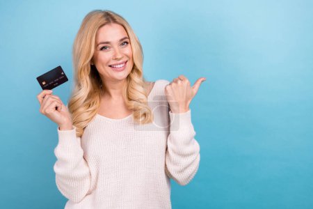 Photo de belle femme adorable porter des vêtements blancs à la mode tenir carte bancaire espace vide isolé sur fond de couleur bleue.