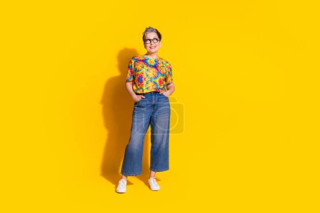 Foto de mujer jubilada encantadora usar ropa de impresión de moda espacio vacío aislado sobre fondo de color amarillo vivo.