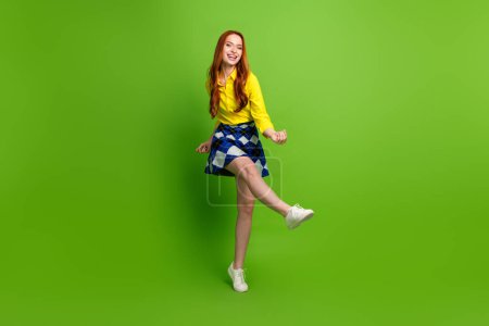 Photo of elegant cheerful cute woman wear yellow trendy clothes dance have fun isolated on green color background.