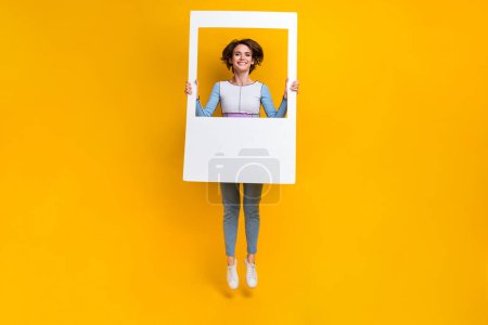 Ganzkörper-Foto von aktiven fröhlichen Dame springen Hände halten Papieralbum Set Karte isoliert auf gelbem Hintergrund.
