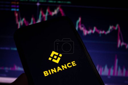 Photo for Binance mobile app logo displayed on the smartphone screen. Blurry stock charts in the background. Afyonkarahisar, Turkey - December 23, 2022. - Royalty Free Image