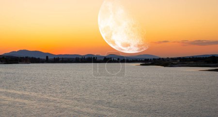 Foto de Vista al lago al atardecer. La Luna en el cielo. Algunos elementos de esta imagen proporcionados por la NASA. - Imagen libre de derechos