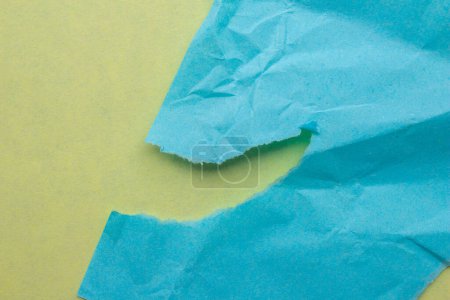 Foto de Pieza de papel azul doblada sobre un fondo amarillo. Fondo de textura de borde de papel desgarrado arrugado. - Imagen libre de derechos
