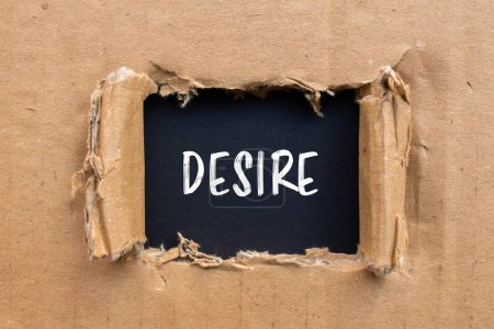 Desire word written on ripped cardboard paper with black backgro