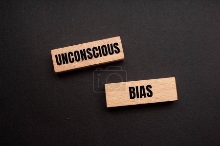 Unconscious bias words written on wooden blocks with black background. Conceptual unconscious bias symbol. Copy space.