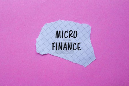 Palabras de micro finanzas escritas en papel blanco rasgado con fondo rosa. Símbolo conceptual del negocio de microfinanzas. Copiar espacio.