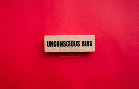 Unconscious bias words written on wooden block with red background. Conceptual unconscious bias symbol. Copy space.