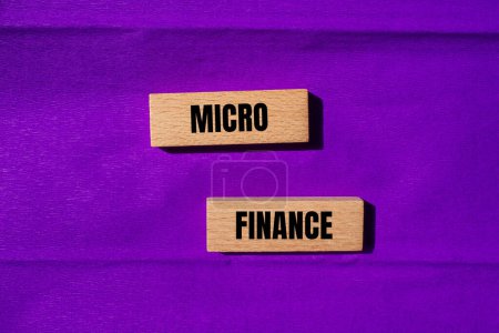 Palabras microfinancieras escritas en bloques de madera con fondo púrpura. Símbolo conceptual del negocio de microfinanzas. Copiar espacio.