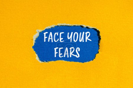 Stellen Sie sich Ihren Ängsten Worte geschrieben auf zerrissenem gelben Papier mit blauem Hintergrund. Konzeptionell stellen Sie sich Ihren Ängsten. Kopierraum.