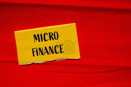 Palabras de micro finanzas escritas en papel amarillo rasgado con fondo rojo. Símbolo conceptual del negocio de microfinanzas. Copiar espacio.