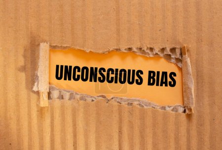Unconscious bias words written on ripped cardboard paper with orange background. Conceptual unconscious bias symbol. Copy space.