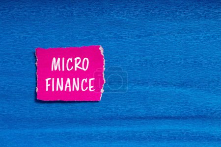 Palabras de micro finanzas escritas en papel rosa rasgado con fondo azul. Símbolo conceptual del negocio de microfinanzas. Copiar espacio.