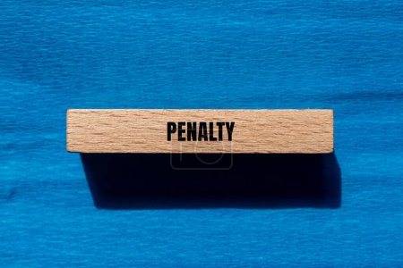 Penalty word written on wooden block with blue background. Conceptual penalty symbol. Copy space.