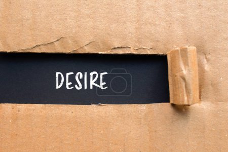 Desire word written on ripped cardboard paper with black background